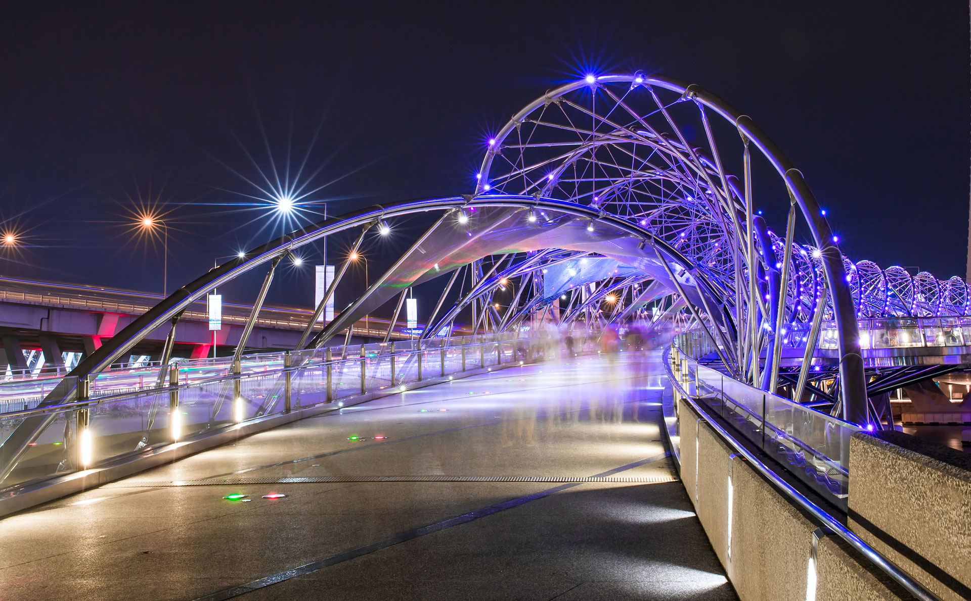 Architectural photo of a geometric bridge support lit up with purple lights