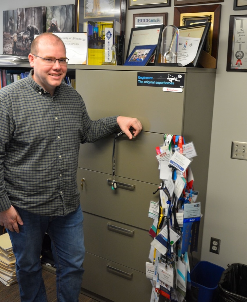 Brandon Grainger standing next to award plaques and many lanyards