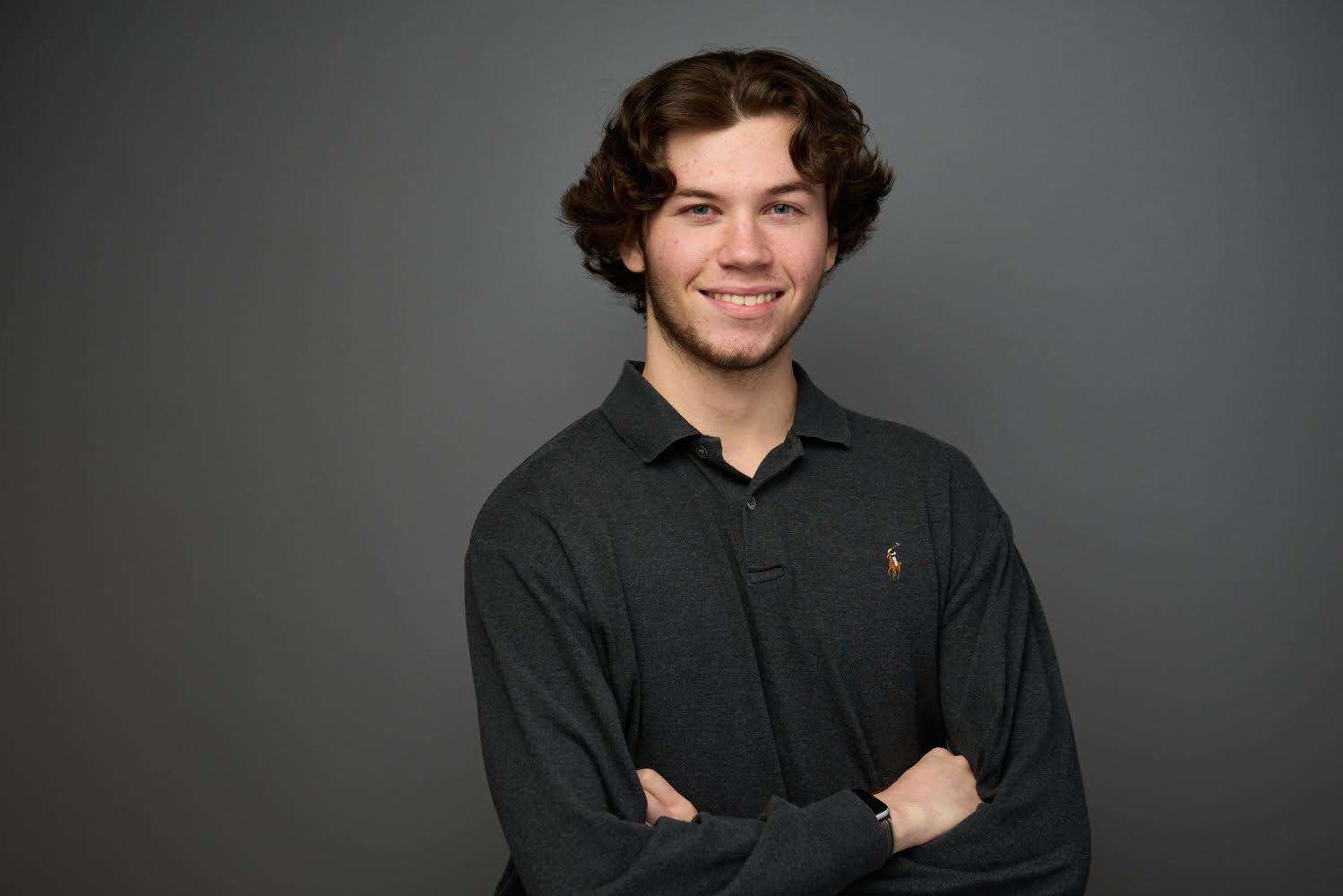 Lucas Connell smiles at the camera with his arms crossed in front of him 