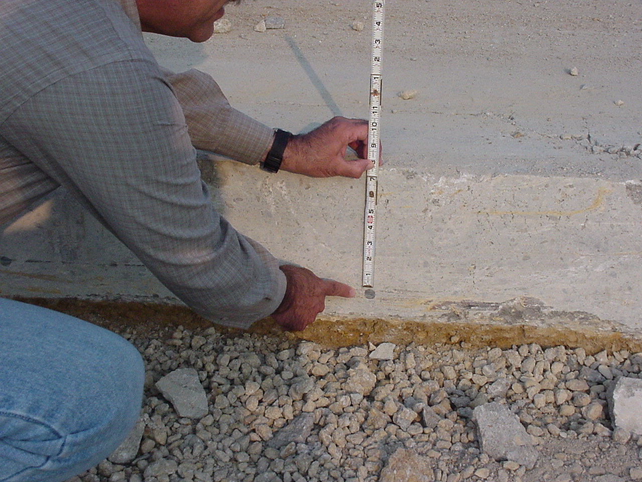 a worker measuring the distance to rebar from the surface of concrete