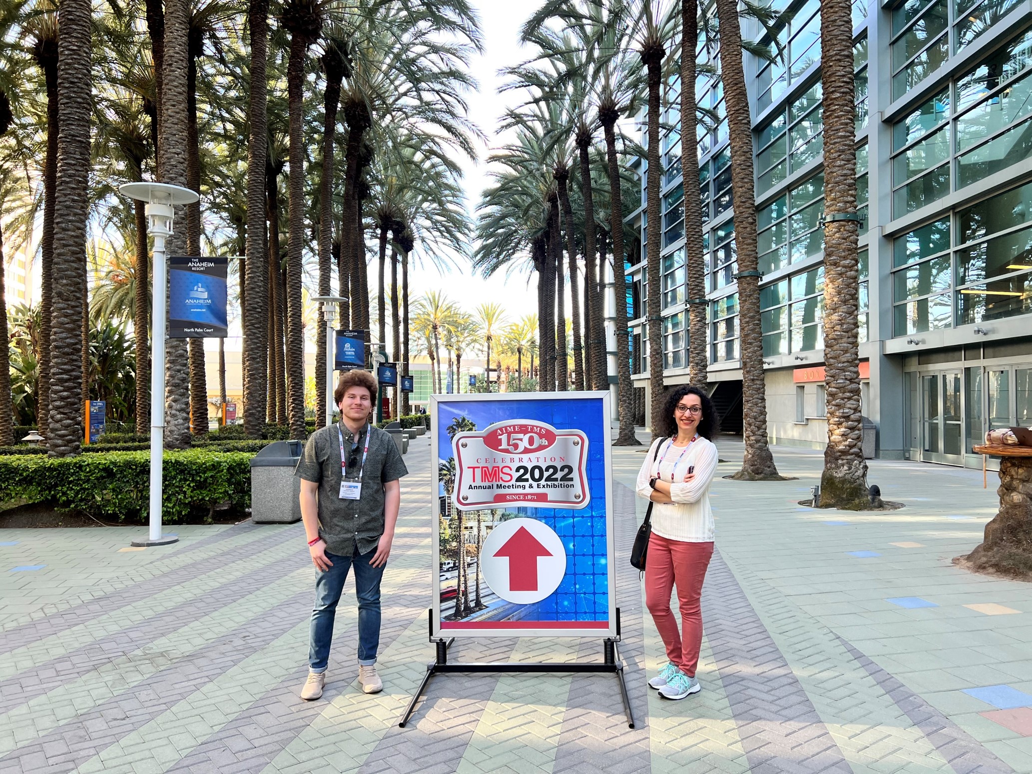 Two people standing next to the TMS 2022 sign