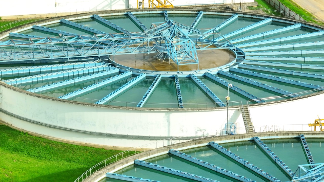 Bird's eye view of a wastewater treatment facility with circular clarifiers and rectangular filtration basins, showcasing critical infrastructure for effective water purification and community