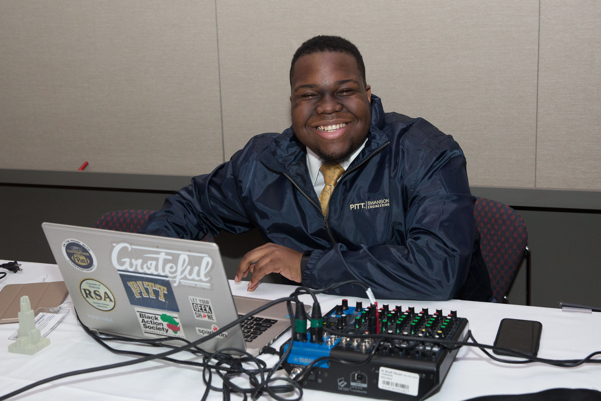 A student working on a laptop smiling