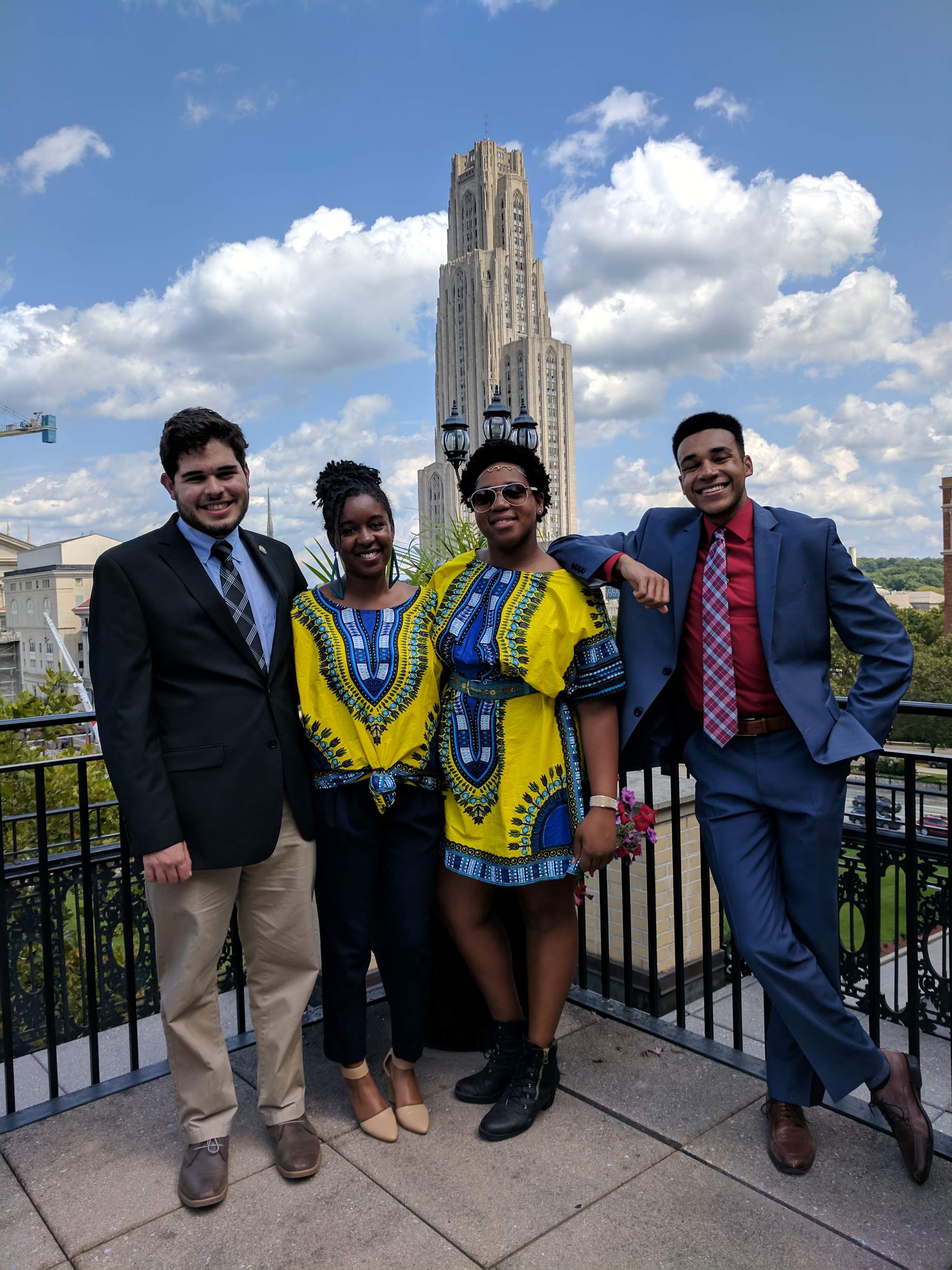 A group of students smiling in front of the cathedral of learning