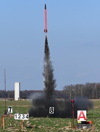 A red rocket launching into the air in a field